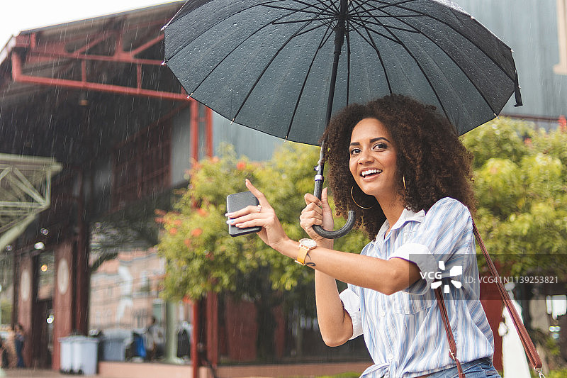 一位年轻女子在雨天叫出租车图片素材