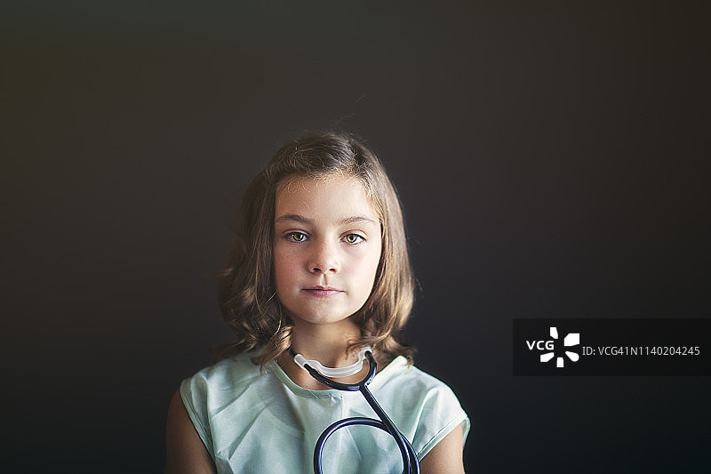 女孩的肖像打扮成护士戴着听诊器看着相机图片素材