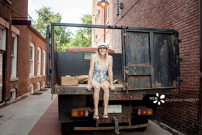 一个女人坐在杂货店外农民的有机食品卡车上图片素材