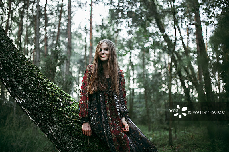 一个女人坐在森林里的一棵树上微笑着图片素材
