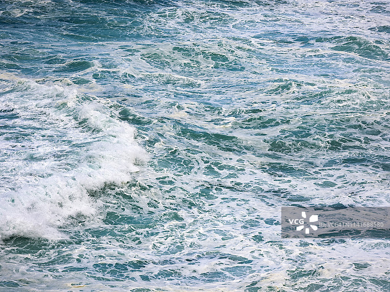 靠近水的海浪与白色泡沫，打破在悬崖上。图片素材