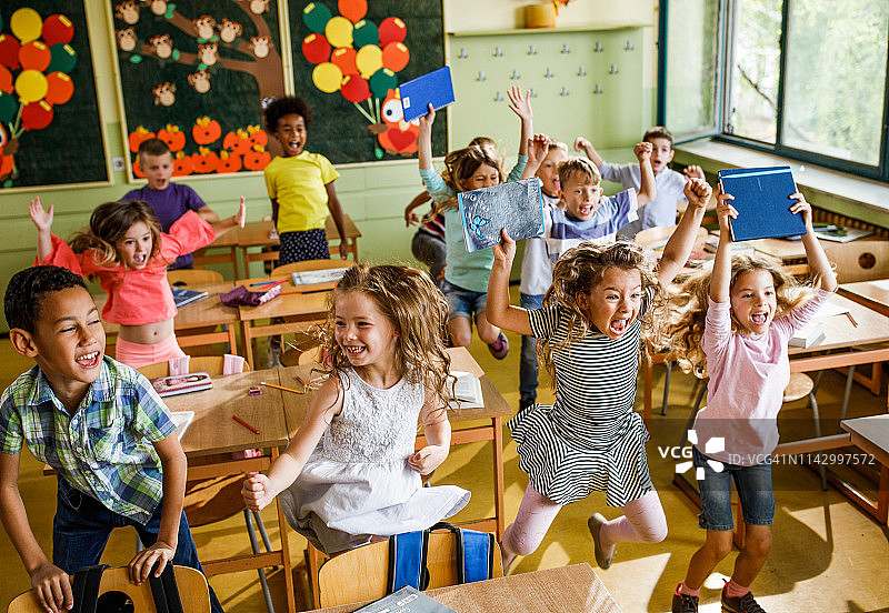 一大群快乐的小学生在教室里跳来跳去。图片素材