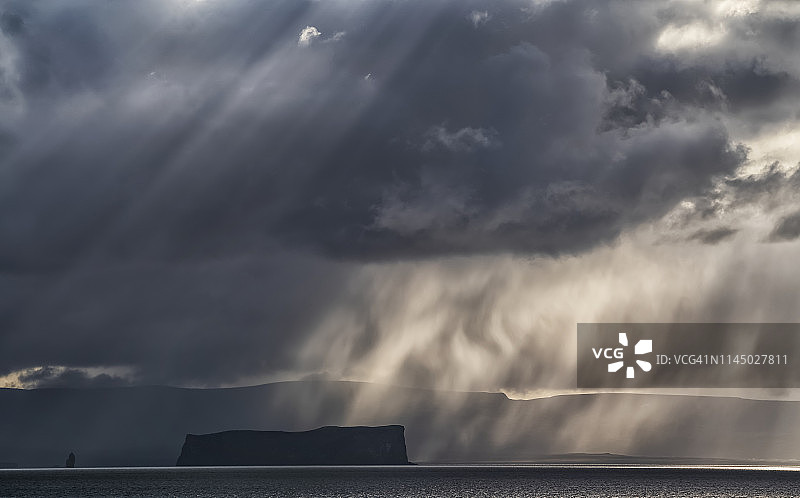 戏剧性的暴风雨云和光在冰岛海岸的一个岛屿上图片素材