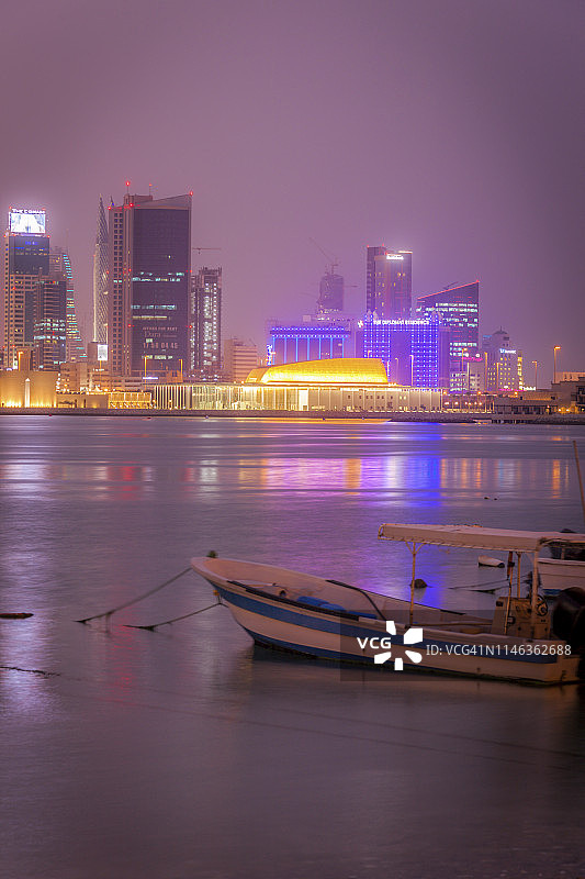 巴林首都麦纳麦，夜间停泊的摩托艇驶过城市天际线图片素材