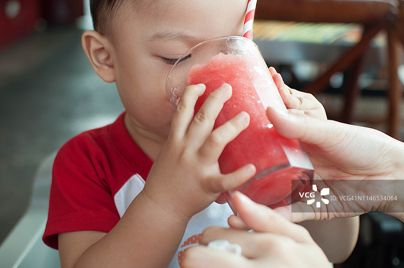 一个小男孩正在喝新鲜的水果奶昔图片素材