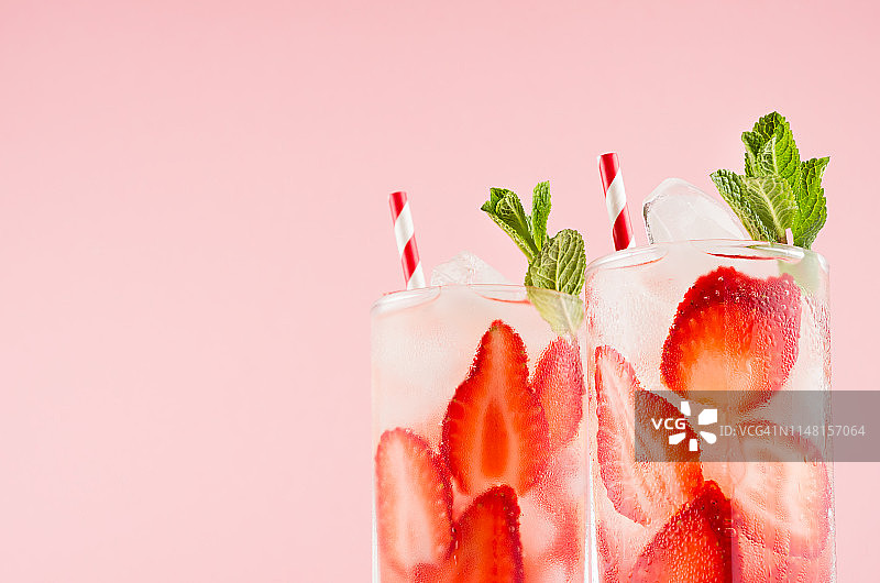 夏日新鲜饮品草莓，冰块，绿薄荷和条纹吸管在粉红色的墙壁上，特写，顶部部分，边缘。图片素材