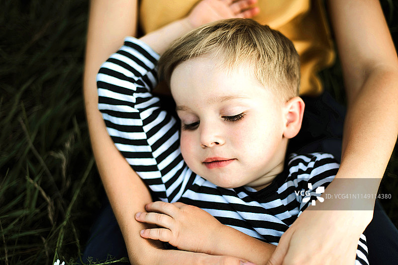 一张母亲和男孩躺在户外的肖像。图片素材