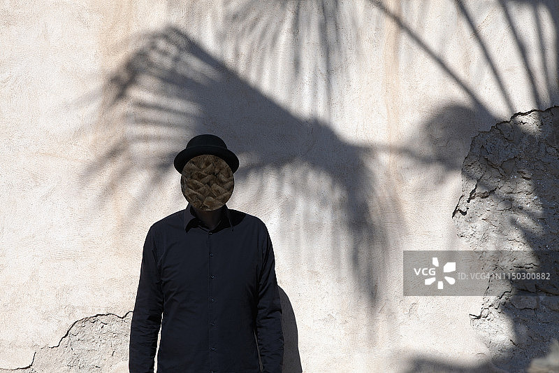 摩洛哥，Essaouira，一名面带圆顶礼帽的男子站在墙边图片素材