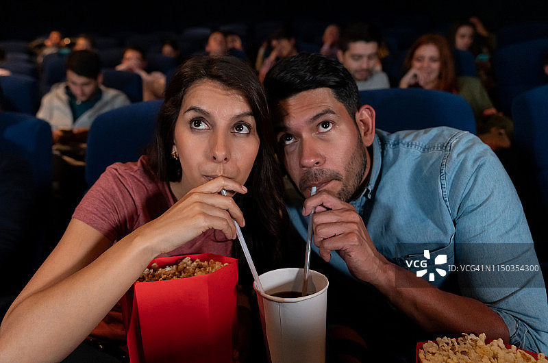 一对幸福的情侣在看电影，一个女人在吃东西，一起喝酒图片素材