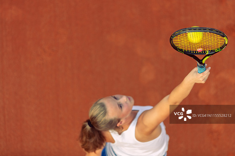 空中拍摄的一个女子网球运动员在一个球场上的比赛。年轻女子在打网球。高角度的观点。图片素材