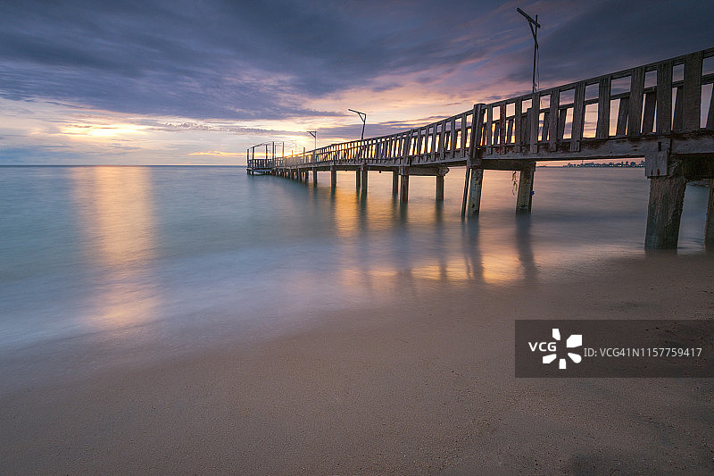 热带海景。日落时分，这座木桥在萨塔希海滩上一直延伸到大海图片素材