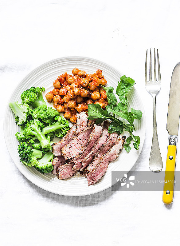 烤牛排，辣炖鹰嘴豆，花椰菜-美味的健康午餐在一个轻的背景，俯视图图片素材