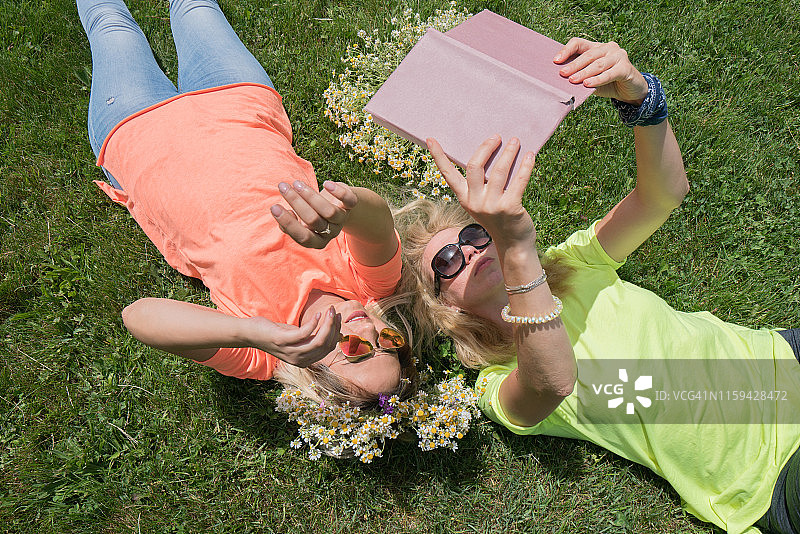 幸福的女人躺在草地上看书图片素材