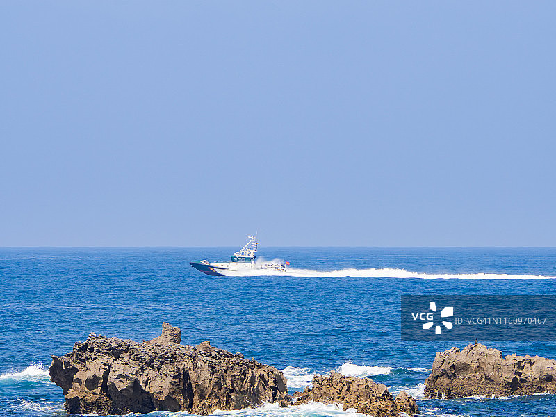 在坎塔布里亚(西班牙)，一艘船在地平线上航行的海岸景观图片素材