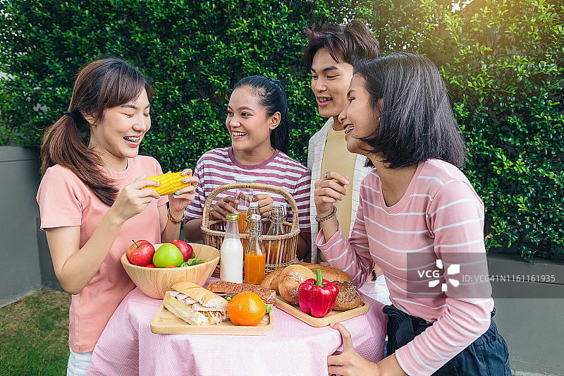 一群快乐的亚洲朋友享受在户外公园野餐，健康的食物和生活理念图片素材