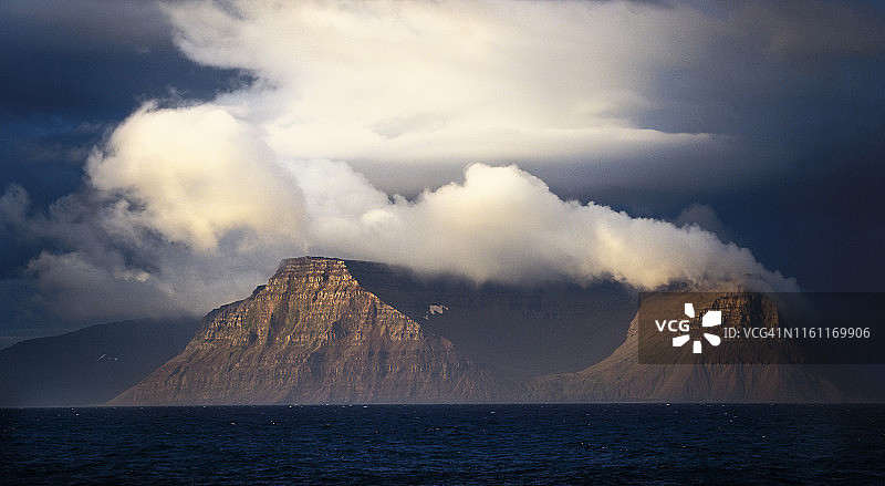 冰岛西峡湾上空被照亮的山脉和云彩图片素材