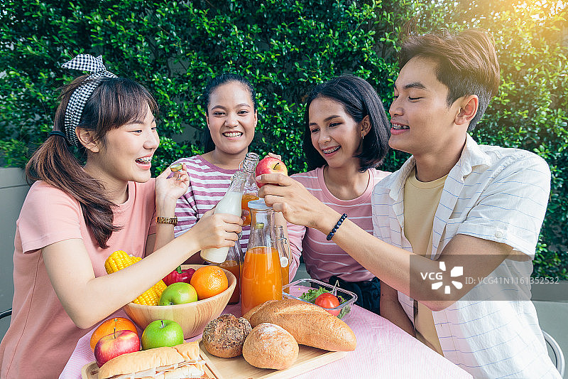 一群快乐的亚洲朋友享受在户外公园野餐，健康的食物和生活理念图片素材
