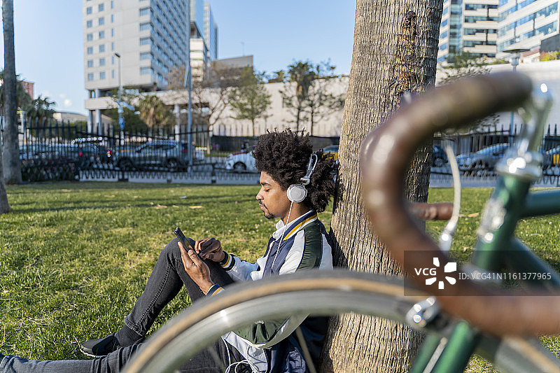 在西班牙巴塞罗那的一个城市公园里，一个漫不经心的商人用手机骑着自行车图片素材