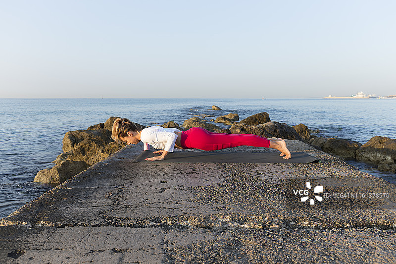一名年轻女子在海滩上练习瑜伽，做着chaturanga dhandasana图片素材