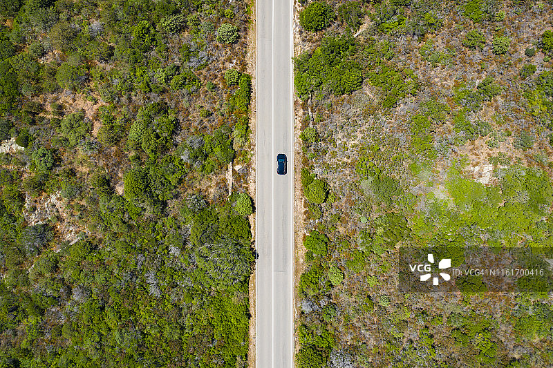 从上面看，一辆汽车沿着绿色森林的道路行驶的令人惊叹的鸟瞰图。意大利撒丁岛。图片素材