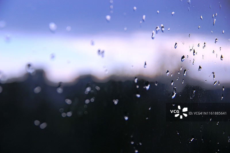 雨滴落在玻璃上，落在窗外城市的背景上图片素材