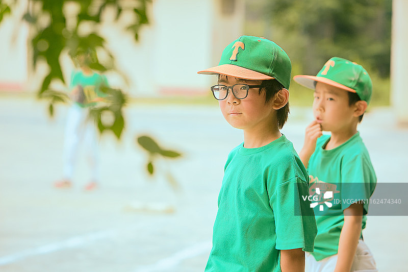 孩子(8-9)棒球朋友看队友在球场上图片素材
