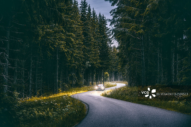 在瑞典斯马兰地区，一辆汽车在夜间行驶在森林里图片素材