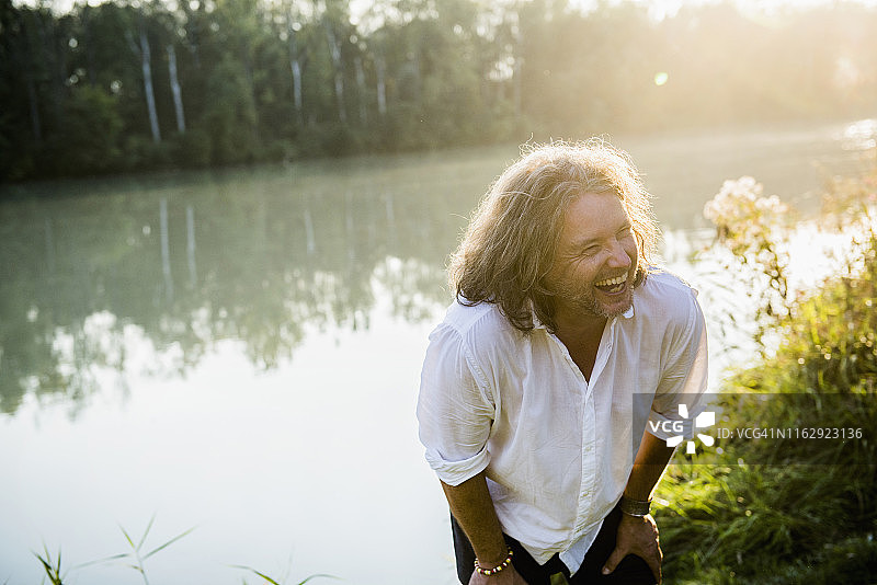 德国巴伐利亚，长头发的快乐男子在河边笑图片素材