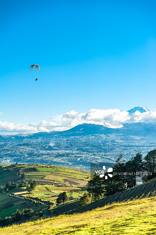 在厄瓜多尔安第斯山脉顶端飞行的滑翔伞教练和游客图片素材