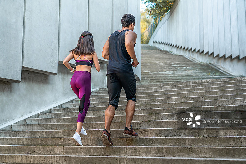 侧面的健康的女人和男人跑上楼梯的城市图片素材