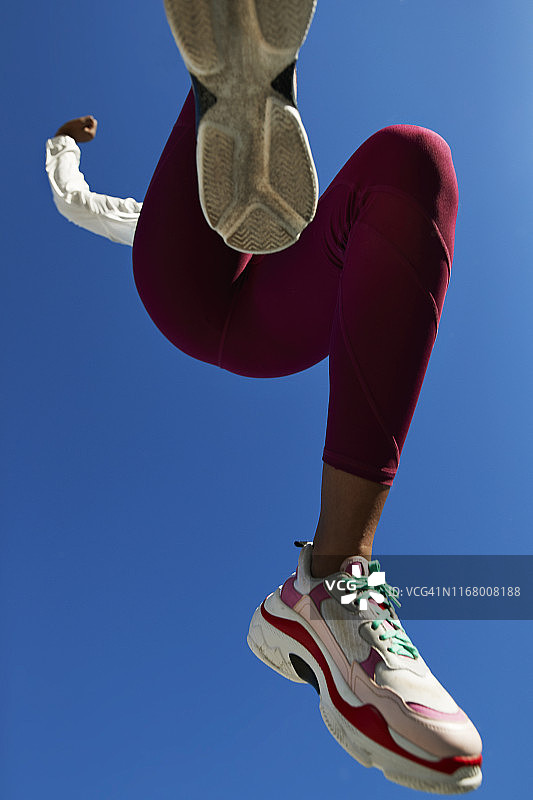 女运动员在湛蓝的天空下跳跃图片素材