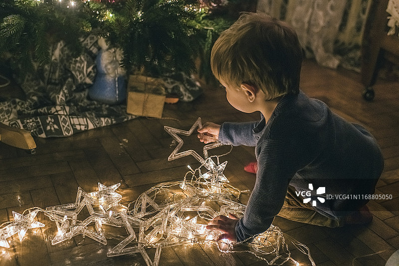 小男孩在家玩圣诞彩灯图片素材