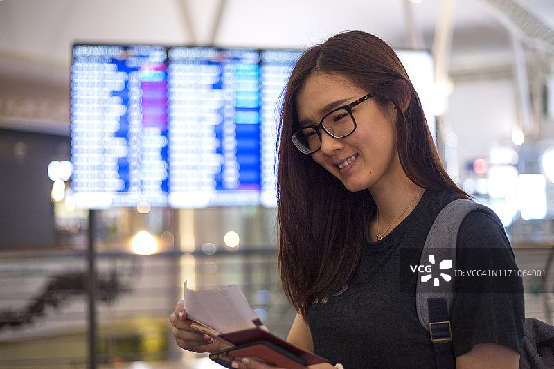 快乐的亚洲女旅行者在机场查看航班行程图片素材