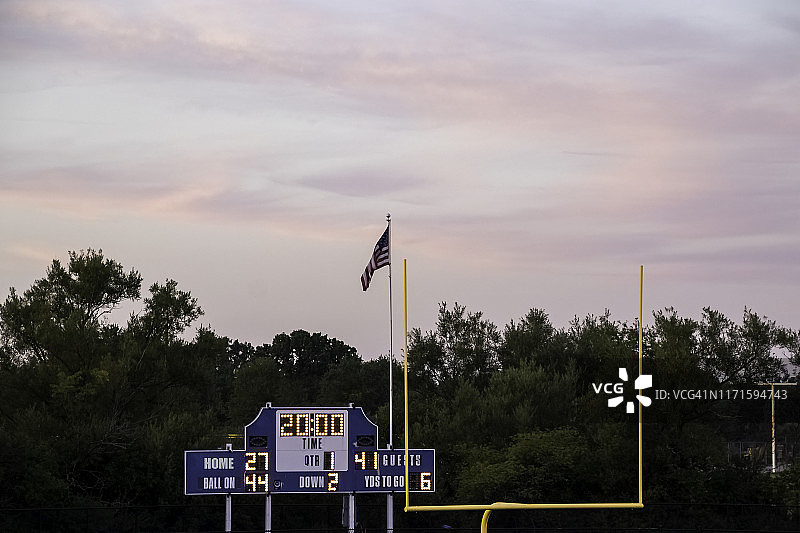 足球结束区与球门，美国国旗和得分板在傍晚日落在当地高中图片素材