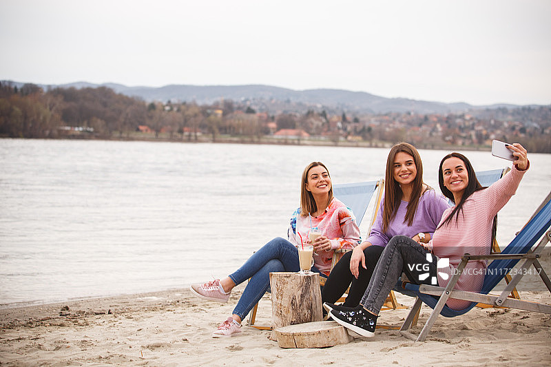 三个微笑的年轻女人在海滩上自拍图片素材