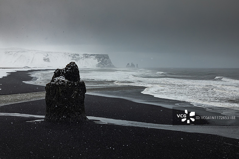 冬天，黑色火山海滩上下雪。冰岛图片素材