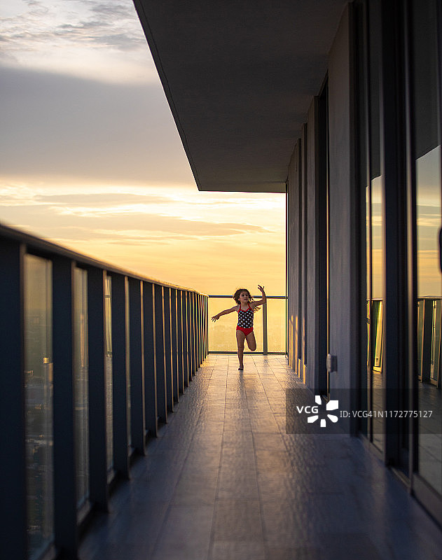 日落时分，女孩在迈阿密一栋建筑的阳台上跑步和玩耍图片素材