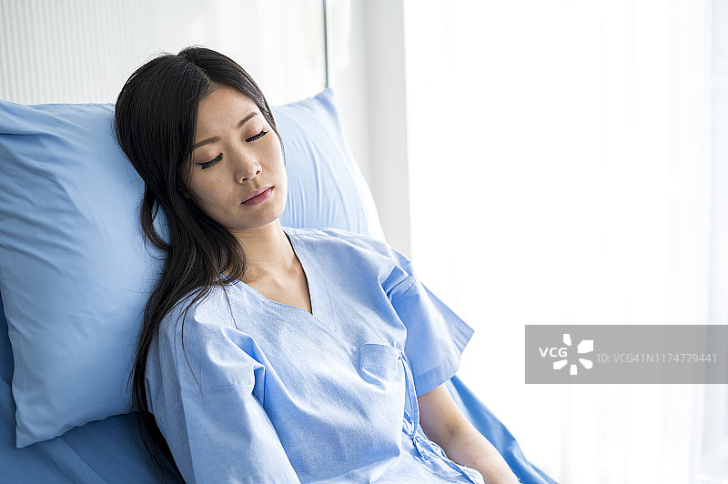 病房里一个生病的女人闭着眼睛躺在床上。图片素材