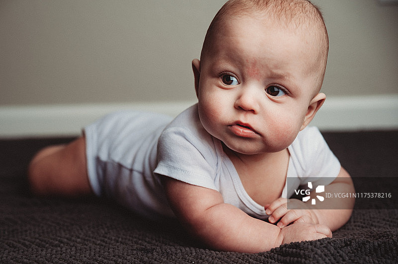 7个月大的男婴坐在明亮的家庭工作室的地毯上图片素材