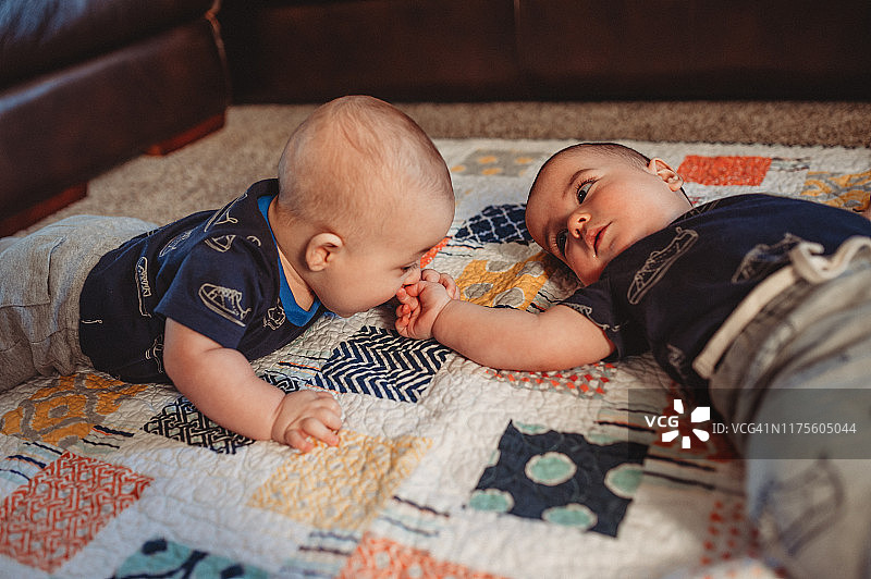 胖乎乎的6个月大的双胞胎在做俯卧时间的时候一起玩图片素材