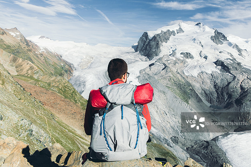 一个背包客在瑞士阿尔卑斯山欣赏着巨大的冰川和山脉图片素材
