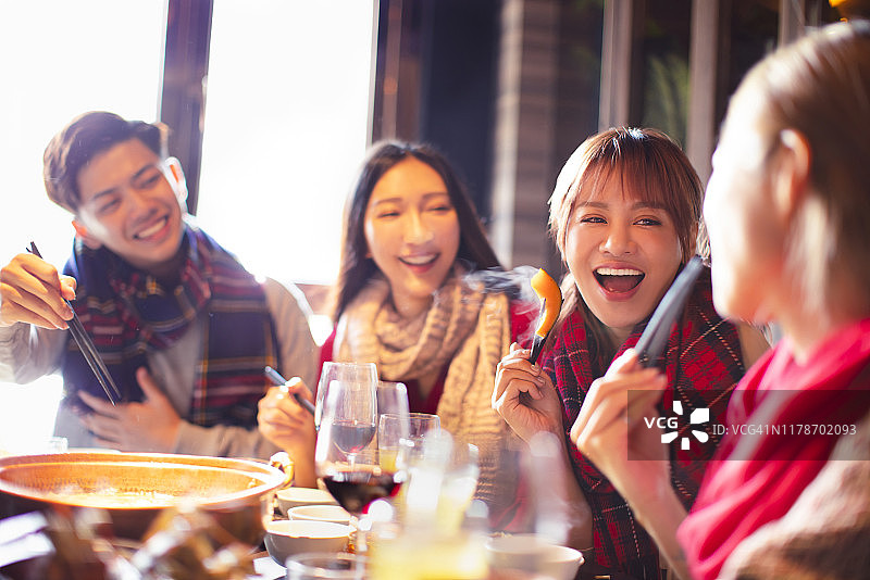 快乐的年轻朋友们冬天在餐馆吃火锅图片素材
