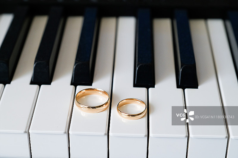 钢琴琴键上放着结婚的金戒指。图片素材