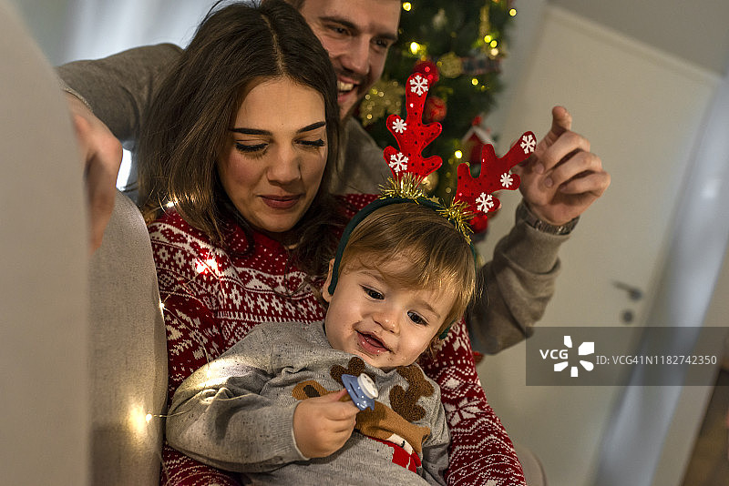 快乐的父母和婴儿在装饰的房间为圣诞节图片素材