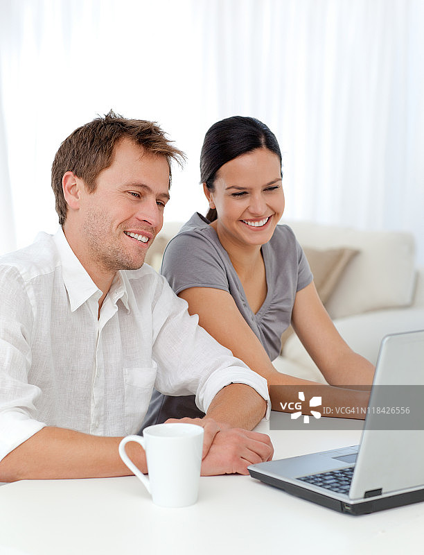 一对可爱的夫妇一边在笔记本电脑上看视频一边大笑图片素材
