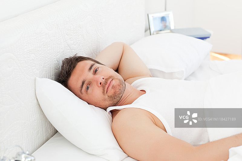 一个放松的男人在他的床上醒来图片素材