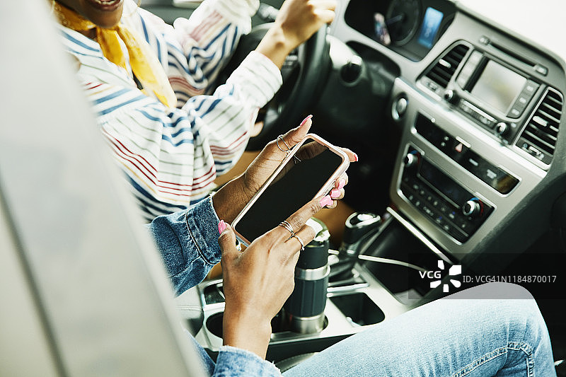 女乘客坐在汽车副驾驶座上看智能手机图片素材