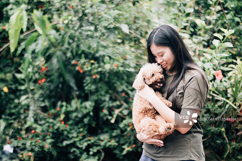 十几岁的亚洲女性拥抱和抱着宠物贵宾犬的肖像图片素材