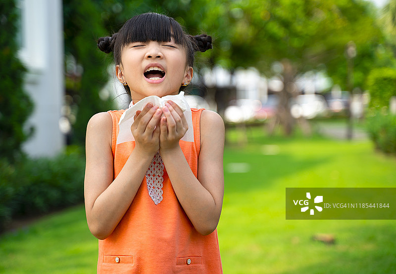 生病的亚洲小女孩用纸巾擦鼻子图片素材