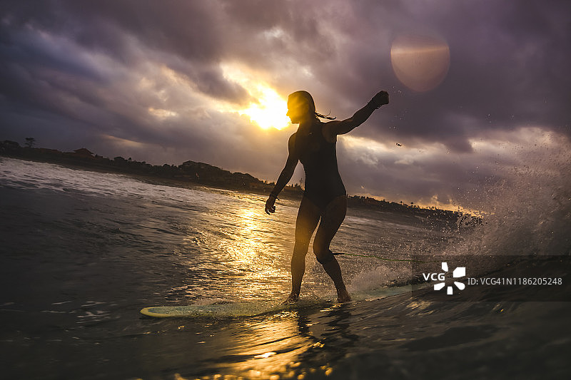 年轻女子在日落时冲浪图片素材